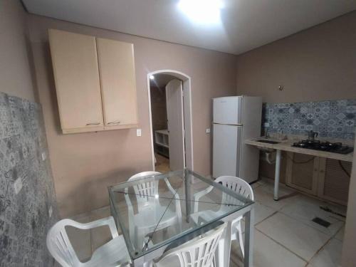 a kitchen with a glass table and white chairs at Seasonal or student flat near Cachoeira in Campo Grande
