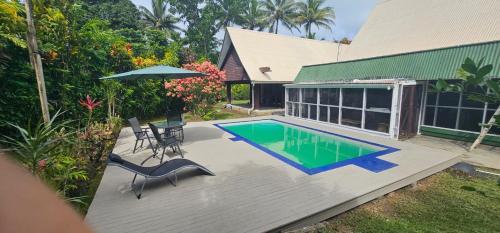 a patio with a pool and a table and an umbrella at Villa Serenity welcomes you in Pacific Harbour