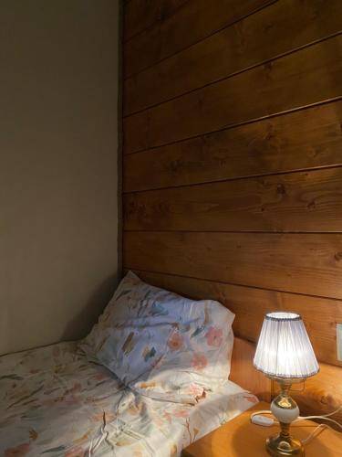 a bed with a wooden headboard next to a table with a lamp at Dom Na Wsi ,, Koszelówka " in Koszele