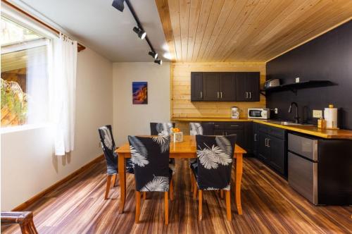 a kitchen with a wooden table and black cabinets at Halema'uma'u- Hale Kumu La'au in Volcano