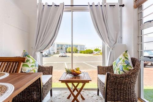 a dining room with a table and chairs and a large window at Caline-V Luxury beach Front Flat in Cape Town