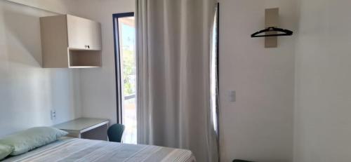 a bedroom with a bed and a window and a desk at AP Praia - Vog 2 quartos com AR e D'Ouro Park-Rua dos Tangarás, 20 todo climatizado in Ilhéus