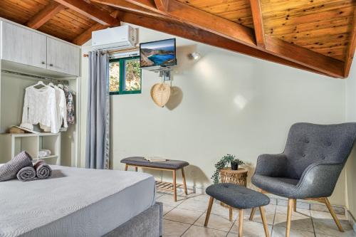 a bedroom with a bed and two chairs at Elena's Seafront Deluxe Studios in Zakynthos
