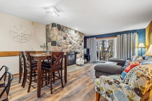 ein Wohnzimmer mit einem Tisch und einer Steinmauer in der Unterkunft Large 2 Floor Condo, Pool Pass, Beach Club, walk to Shanty Creek in Bellaire
