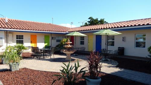 a house with a patio with tables and chairs and umbrellas at Haven Hotel - Fort Lauderdale Airport & Cruise Port in Fort Lauderdale