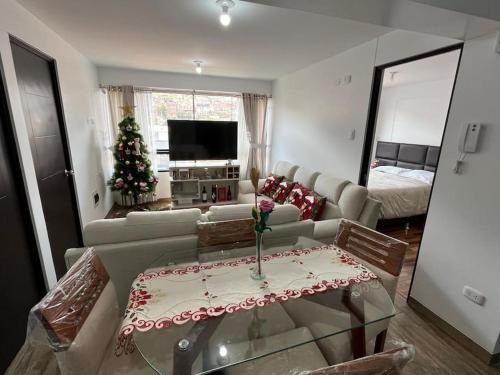 a living room with a couch and a table and a christmas tree at Apartamento de estreno en Cusco in Cusco