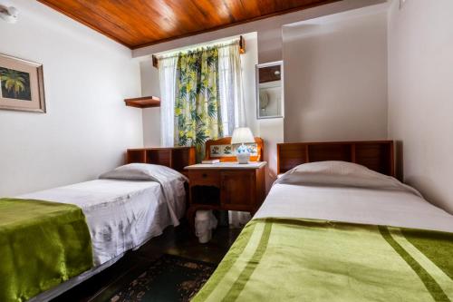 a bedroom with two beds and a table and a window at Cholson Chalets in Charlotteville