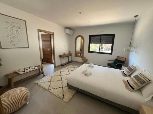 a bedroom with a large white bed and a chair at Villa vue sur le Golf 1 in Olmeto
