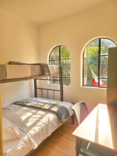 a bedroom with two bunk beds and two windows at Guest House del Valle in Mexico City