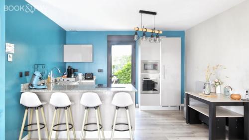 a kitchen with blue walls and white stools at Gîtes Rozanna avec accès détente SPA JACUZZI in Saint-Jean-de-la-Rivière