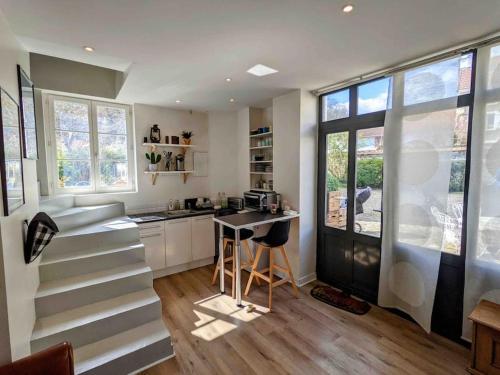 - une cuisine avec des escaliers, une table et quelques fenêtres dans l'établissement Adorable petite maison indépendante avec parking privé, à Le Mesnil-le-Roi