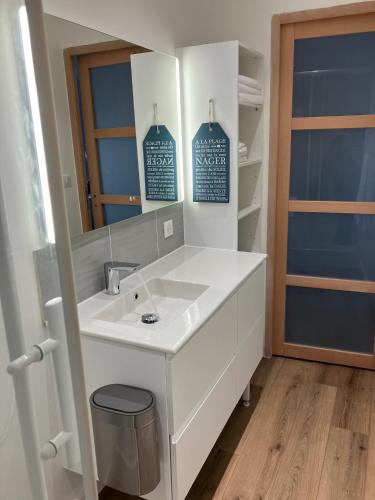 une salle de bain avec un lavabo blanc et un miroir dans l'établissement Appartement - St Brevin Les Pins - Hyper Centre - Fibré - Parking - Jusqu'à 6 personnes, à Saint-Brévin-les-Pins