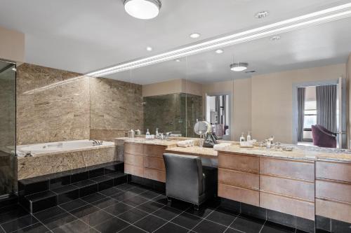 a bathroom with two sinks and a bath tub and a chair at Hotel De Anza in San Jose