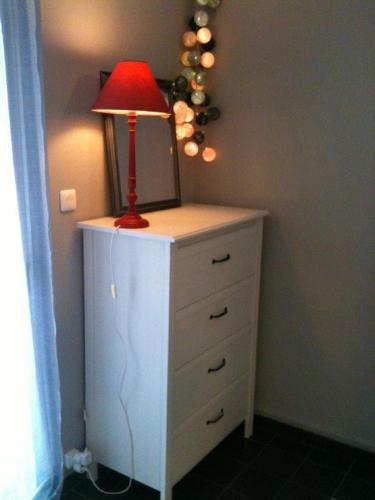 une lampe rouge posée sur une commode dans l'établissement Appartement Les Thermes II, à Balaruc-les-Bains