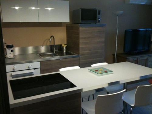 - une cuisine avec un comptoir, un évier et une table avec des chaises dans l'établissement Appartement Les Thermes II, à Balaruc-les-Bains