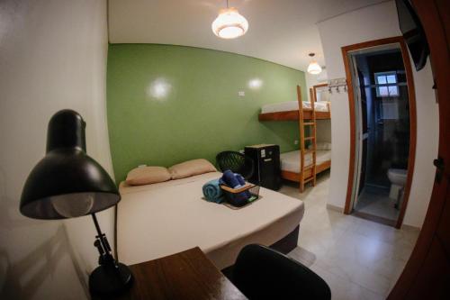 a room with a green wall with a bed and a lamp at Atlantic Pousada in São Sebastião