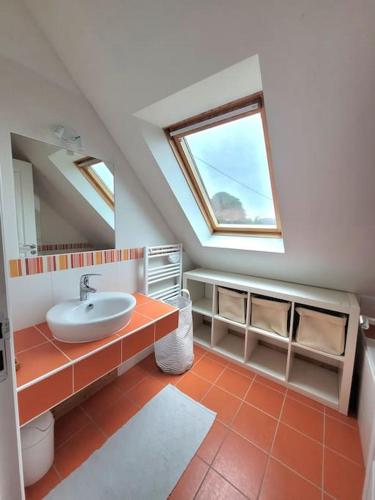 une salle de bains mansardée avec lavabo et fenêtre. dans l'établissement Maison plain pied 5 CH, littoral sud pays Bigouden, à Penmarcʼh