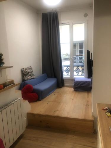 un salon avec un canapé bleu et une fenêtre dans l'établissement Studio 2 pers - Cœur de Paris, à Paris