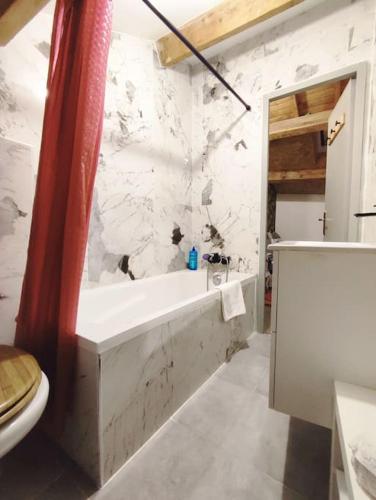 La salle de bains blanche est pourvue d'une baignoire et de toilettes. dans l'établissement logement près des volcans, à Durtol