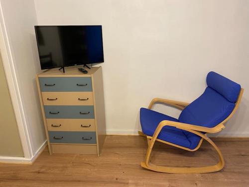 a blue chair next to a dresser and a television at Bel appartement avec place de parking privative in Aix-les-Bains