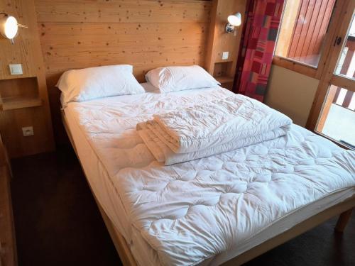 Elle comprend un grand lit avec des draps et des oreillers blancs. dans l'établissement Résidence Le Boulier - Bel appartement spacieux MAE-2411, à Aime La Plagne