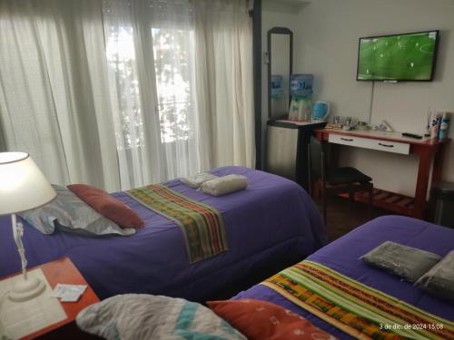 a bedroom with two beds and a desk and a television at Buenos Aires, CABA in Buenos Aires