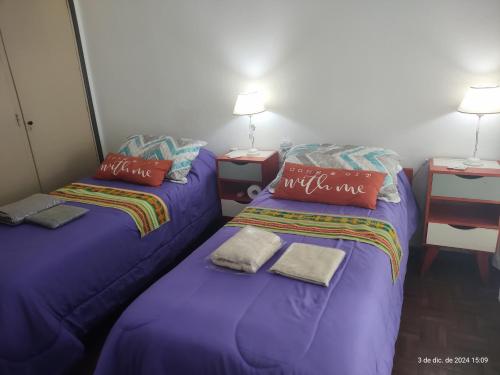 two beds in a room with purple sheets and pillows at Buenos Aires, CABA in Buenos Aires