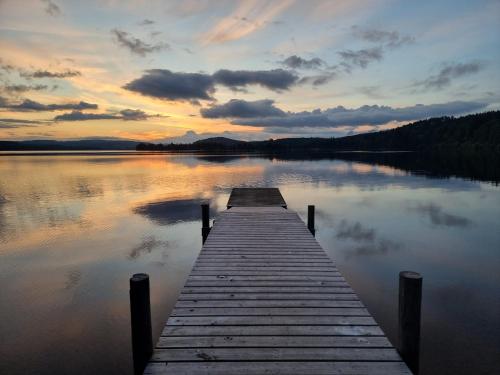 a wooden dock on a lake with a sunset at Sunne Stugcenter 12 in Gräsmark