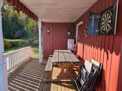 a wooden porch with a table and a dartboard on the wall at Sunne Stugcenter 12 in Gräsmark