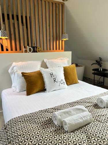 un lit blanc avec des oreillers et des serviettes dessus dans l'établissement Le 70 Sainte Marine, à Combrit