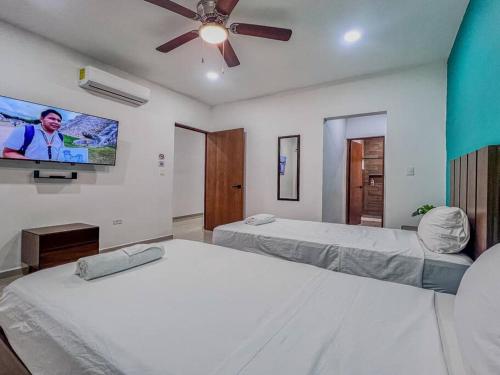 a bedroom with two beds and a flat screen tv at 4 Br semi luxury house in downtown with pool - Casa San Juan in Valladolid