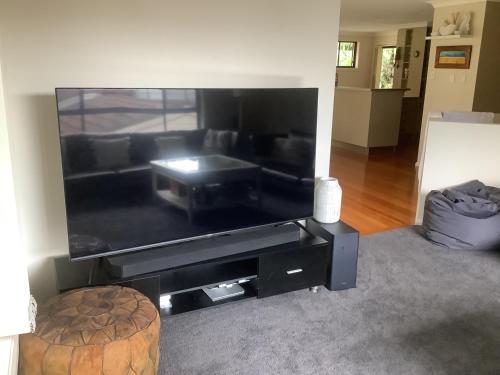 a living room with a large flat screen tv at 4 Bedroom modern house opposite Wallis Lake in Forster