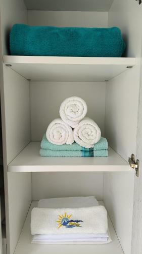 two towels and a blue towel on a shelf at Maraújosflat, Porto de Galinhas in Porto De Galinhas