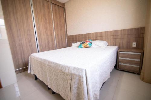 a small bedroom with a bed with a white blanket at Casa c/4 quartos e Piscina - Excelente localização in Caldas Novas