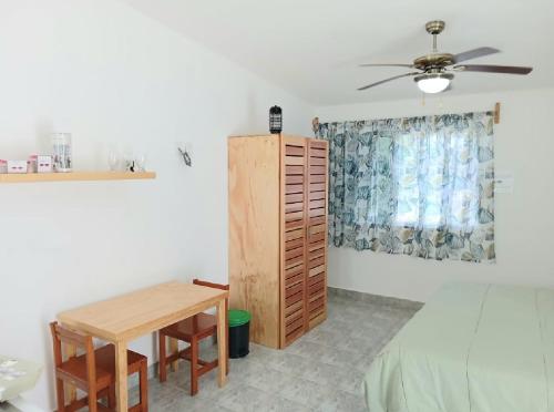 a bedroom with a table and a bed and a ceiling fan at Estudio Coatí Azul en la Isla de Cozumel en el Caribe in Cozumel