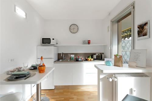 une cuisine blanche avec une table et une horloge murale dans l'établissement Lumiere Du Matin San Felice - Happy Rentals, à Menton