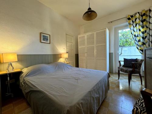 une chambre avec un lit, une chaise et une fenêtre dans l'établissement Le petit Paradis - vue mer - Piscine, à Sanary-sur-Mer