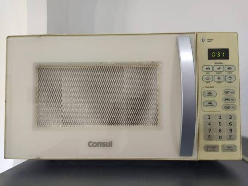 a white microwave oven sitting on top of a counter at 101 Apt funcional prox ao centro in Vitória da Conquista