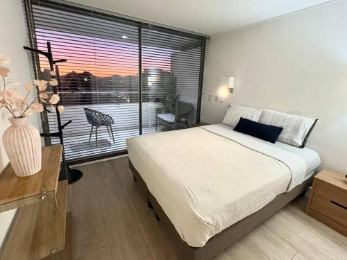 a bedroom with a bed and a window with a table at Las Condes De Lujo in Santiago