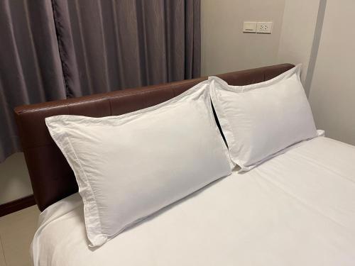 a bed with two white pillows and a brown headboard at ท่าช้างรีสอร์ท กาญจนบุรี in Kanchanaburi