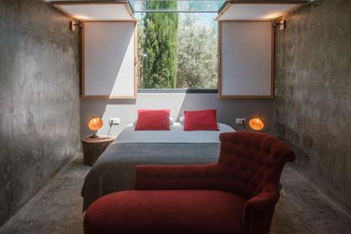 Schlafzimmer mit einem Bett mit einem roten Stuhl und einem Fenster in der Unterkunft BABhouse Villa Jardim das Oliveiras in Nagoselo do Douro