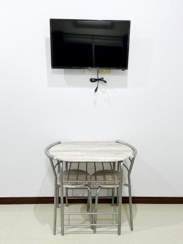 a table with a chair and a tv on a wall at ท่าช้างรีสอร์ท กาญจนบุรี in Kanchanaburi