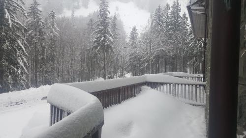 a snow covered porch with a fence and trees at Bilocale nel Resort con terrazzo - Val di Luce in Abetone