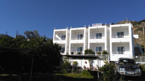 a white building with a car parked in front of it at Antouan Matina in Archangelos
