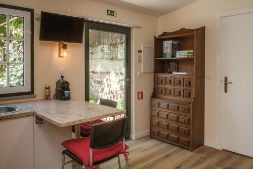 a kitchen with a counter and red chairs in a room at BABhouse Villa Jardim das Laranjeiras in Nagoselo do Douro