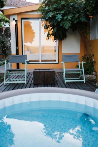 a pool in front of a house with two chairs at BABhouse Villa Jardim das Laranjeiras in Nagoselo do Douro
