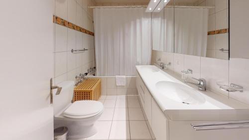 a white bathroom with a toilet and a sink at Apartment Skyline 307 in St. Moritz