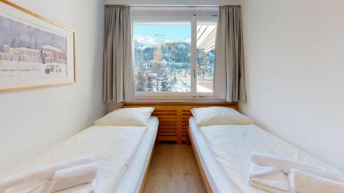 two beds in a room with a window at Apartment Skyline 307 in St. Moritz