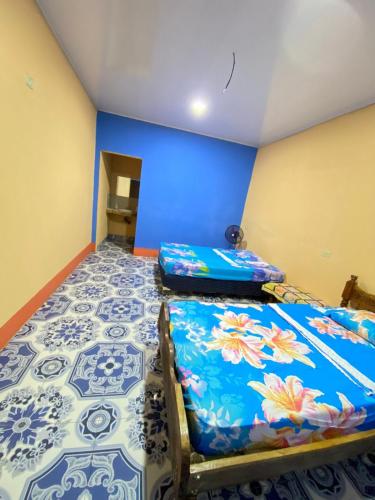 a bedroom with two beds and a blue wall at Casa Caimana in Moyogalpa