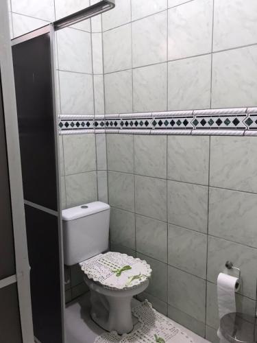 a bathroom with a toilet in a tiled room at Casa da vila in Imbituba